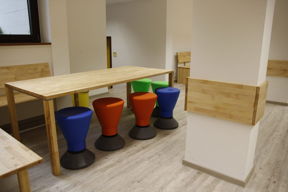 Aufenthaltsecken mit Tischen und bunten Hockern